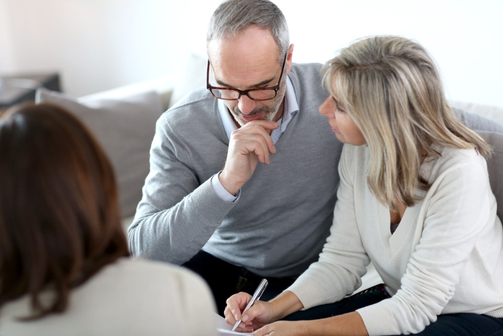 A couple signing paperwork with a financial adviser